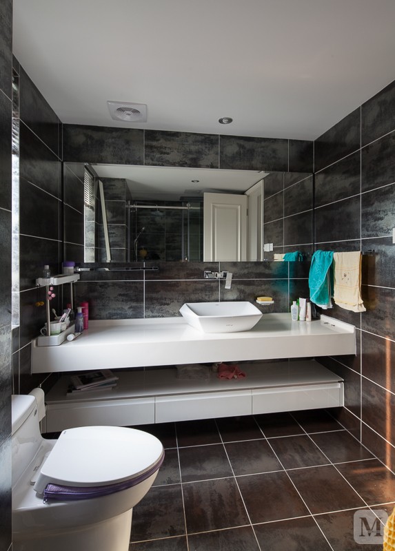 卫生间为深色地砖上墙,整体浴室柜结合单洗手盆的台上盆,以及正面墙的