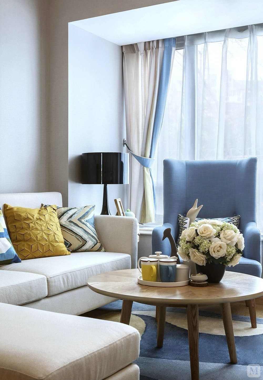 米白色的布艺沙发搭配黄蓝相间的抱枕,不落地的飘窗让客厅变得温馨